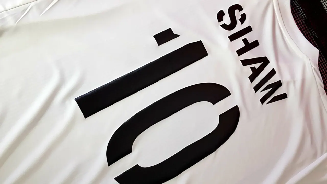 Black name and number printed on the back of a white football shirt