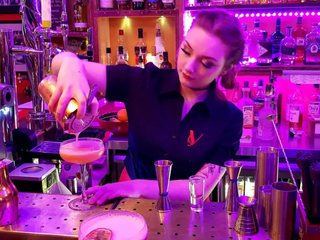 Young lady pouring cocktail embroidered blouse