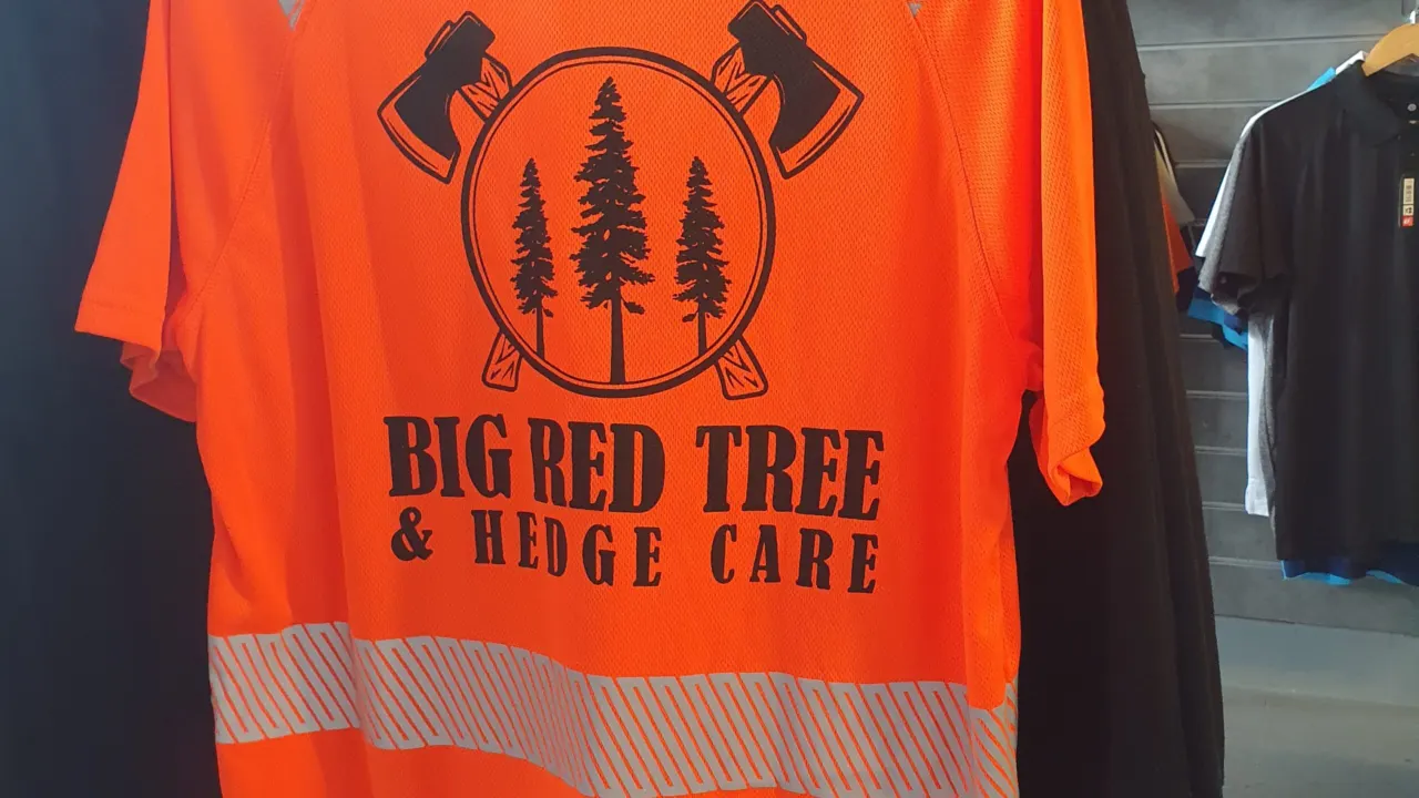 Orange hi-vis work t-shirt printed with a tree surgeon's logo, hanging in the Teepig shop